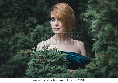 Beautiful girl standing among the trees. She smiles
