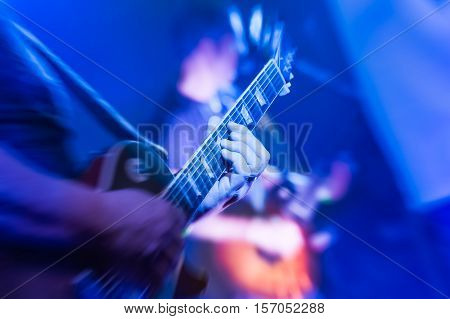 musician playing an electric guitar under blue stage lighting