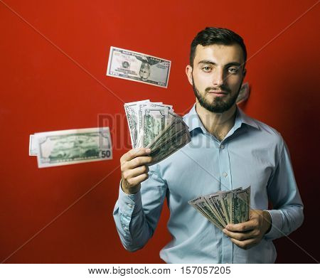 Attractive man with falling dollars banknotes red background, jackpot concept