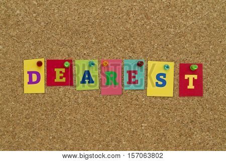 Dearest word written on colorful sticky notes pinned on cork board.