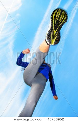 Running and jumping over the camera. Speed and action composition. Shallow depth of field, focus on the female running shoe.