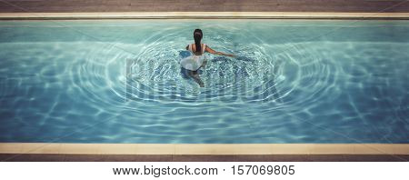 young female in dreaa in the pool at sunset