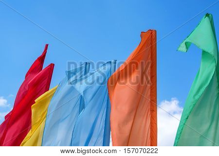 many colorful flags waving over the blue sky background