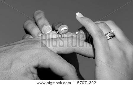 Bride places a gold wedding band on her husbands finger.