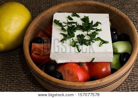 Greek salad with feta cheese and vegetables on wooden plate