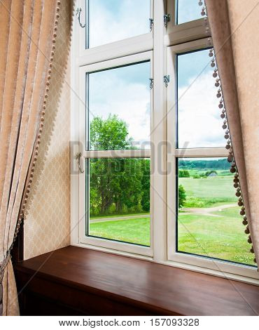 Window with curtains view of summer meadow