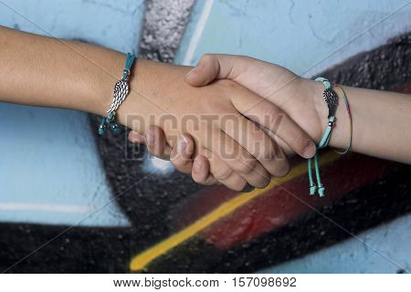 Elche, Spain. October 23, 2016: Two hands of friends caught on a background painted with graffiti.