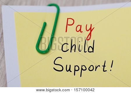 Close-up Of Paper Note Showing Pay Child Support With Green Staple