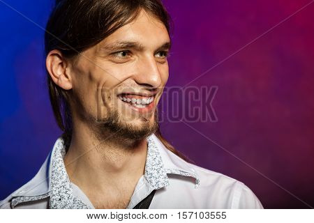 Fashion masculinity concept. Smiling man with long hairs. Young male cheering on colorful red blue background.