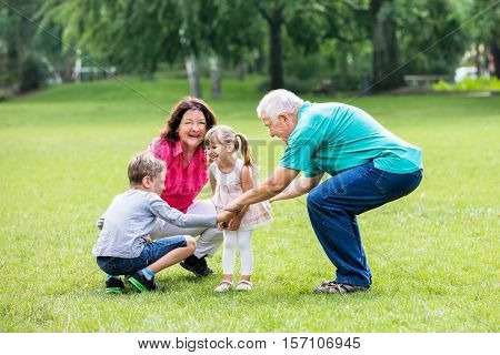 Happy Old Grandparents Having Fun With Grandchildren In Park