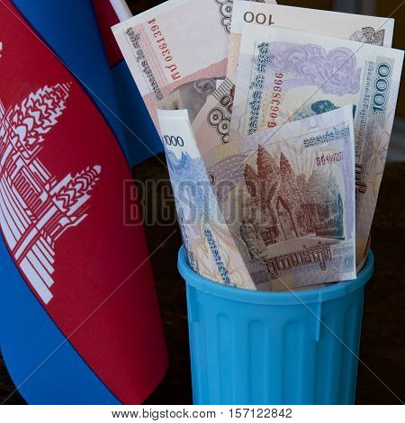 Cambodian riel and flag in a garbage bin.