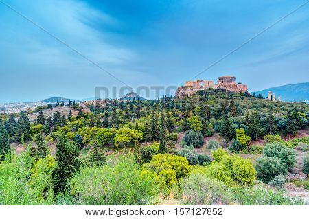Parthenon and Herodium construction in Acropolis Hill in Athens, Greece. Beautiful landscape with green trees around ancient architecture.