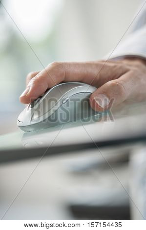 Hand of man using his forefinger to control a cordless mouse on green glass table