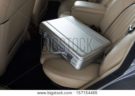 Luxury metal briefcase on a vinage car back seat. Creme leather