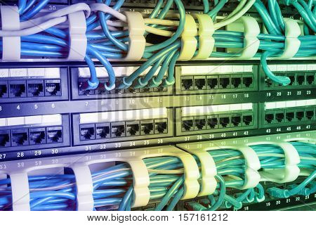 Server rack with blue internet patch cord cables connected to patch panel in server room. Gradient