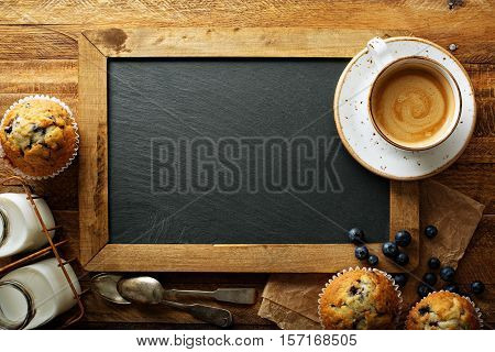 Freshly baked blueberry muffins on chalkboard with milk and coffee on the table overhead shot with copyspace