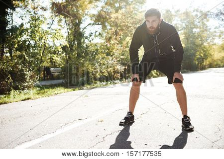 Young tired runner in park. front view