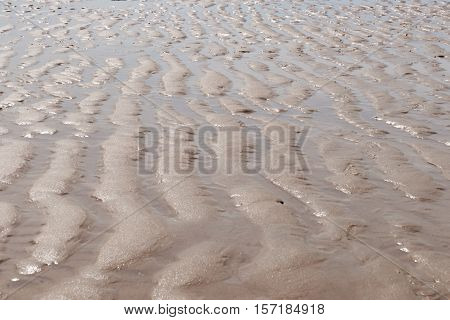 Abstract background of natural pattern left behind in the sand on the shore of an empty beach
