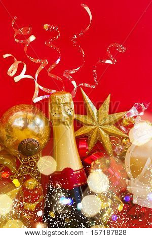 new year decorations with bottle of champagne on red background flat lay scene with bokeh bright lights