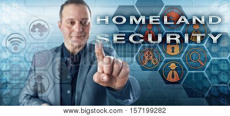 Happy male agent in business suit with toothless smile is activating HOMELAND SECURITY on an interactive control screen. Law enforcement metaphor and security industry concept for homeland defense.