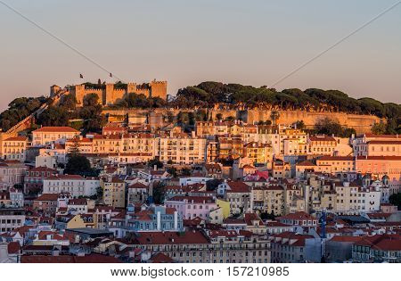 Cityscape of Lisbon Portugal with the Sao Jorge Castle seen from Miradouro Sao Pedro de Alcantara at sunset.