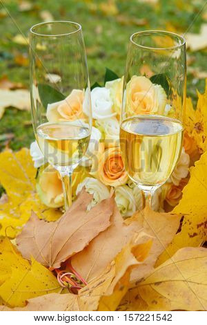 Autumn etude with champagne glasses in yellow maple leaves. Still life in the Park. Rest and celebration of nature in autumn.