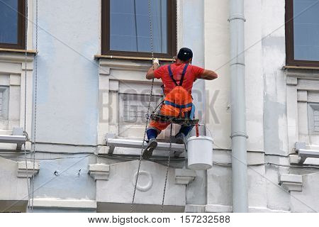 builder worker painting facade of high-rise building with rolle