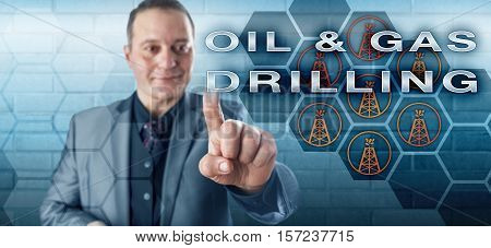 Happy business executive with a toothless smile is touching the phrase OIL & GAS DRILLING on a virtual control screen. Fossil fuel industry concept and technology metaphor for the petroleum market.