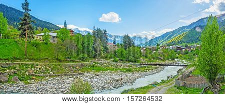 The rocky banks of Mestiachala river with the houses of Mestia and huge mountain ranges on the background Upper Svaneti Georgia.