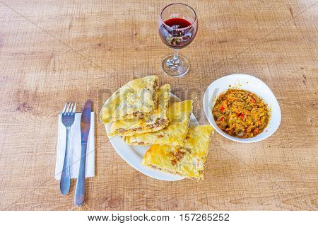 The dishes of Georgian cuisine - kubdari (traditional Svan pie with meat) and ajapsandali (vegetable saute) with the glass of red wine in traditional Georgian restaurant in Mestia Upper Svaneti Georgia.
