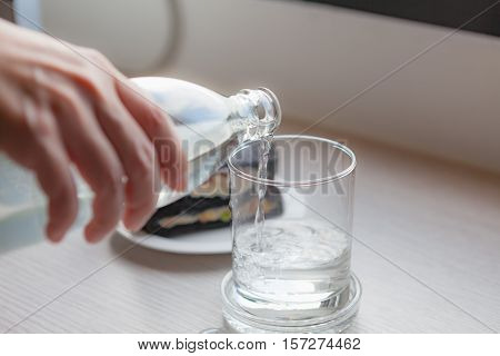 Drinking water is poured from a bottle into a glass