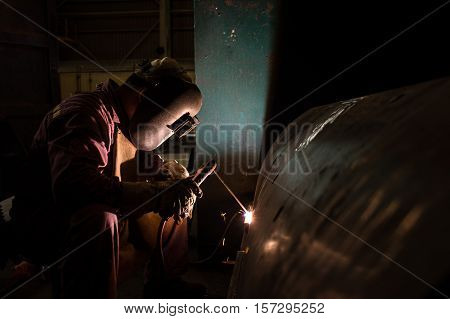 Worker welding repair spare part by SMAW process