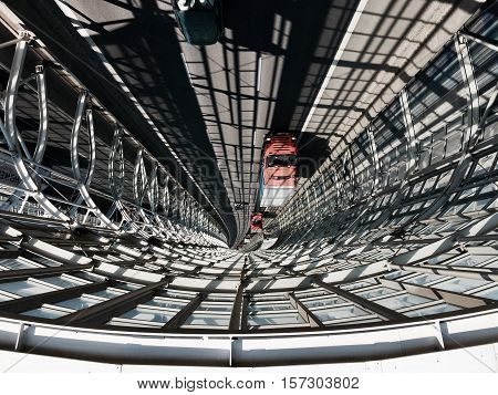 Urban landscape with architectural elements. Indoor glass road for cars. Shadow, sunny day. Contrast. Image is reversed