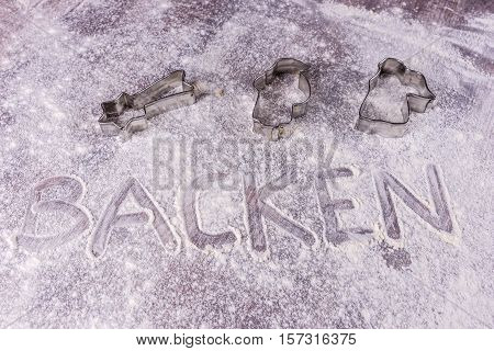 Baking (Backen) in German letters written in flour on the table