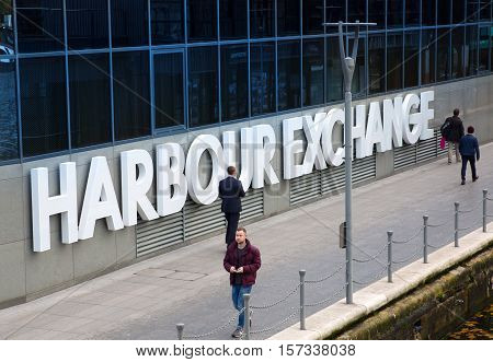 LONDON, UK - November 16, 2016: Canary Wharf. Office workers walking against of Harbour Exchange sign