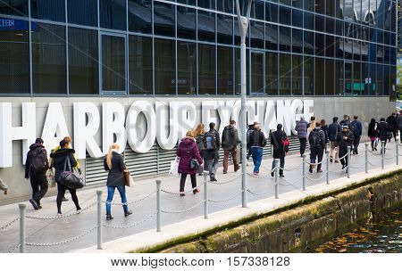 LONDON, UK - November 16, 2016: Canary Wharf. Office workers walking against of Harbour Exchange sign