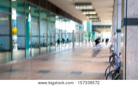 Abstract, blurred image of people walking via long tunnel with light at the background.