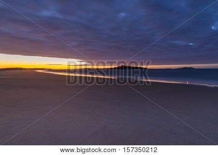 Sunrise at Popham State beach Maine. Smooth samd shore reflecting the cool golden sunlight
