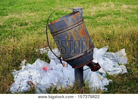 Lots of plastic trash on the ground and empty trash can