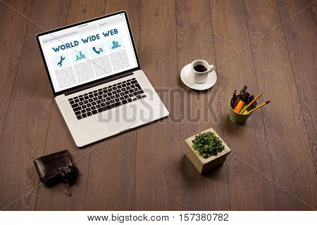 Laptop computer on wooden desk with office suplies