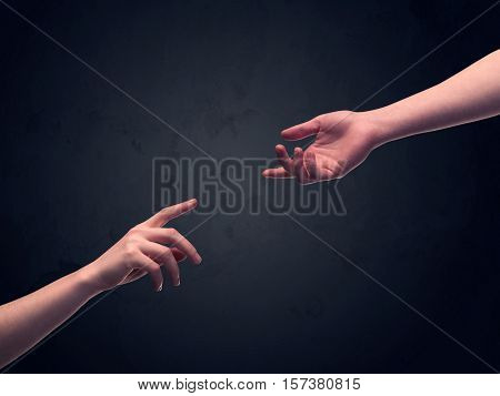 Two male hands reaching out to one another, almost touching, in front of dark clear empty background wall concept