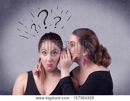A teenager girl looking confused with drawn question marks above the head, while a girlfriend whispers something in her ear concept.