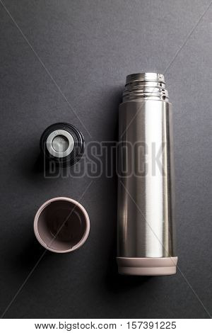Metallic thermos over black background presentation .
