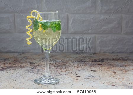 Spritzer cocktail with white wine mint and ice decorated with spiral lemon zest horizontal copy space