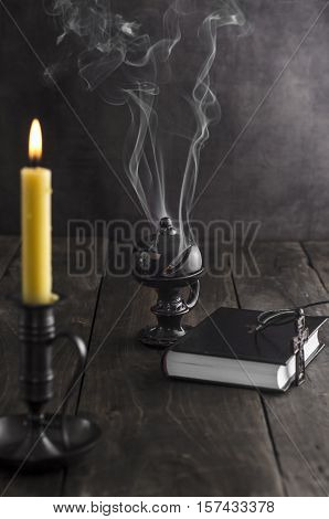 Antique candlestick and burning candle and in the background a incense holder