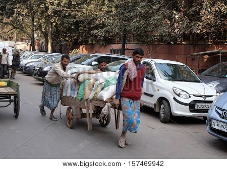 DELHI, INDIA - FEBRUARY 13 : Hard working indians pushing heavy load through streets of Delhi, India on February 13, 2016. Human labour is still cheaper than motorised vehicles.