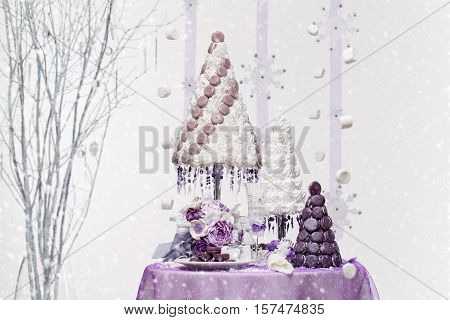 Beautiful set of three handmade white and purple croquembouche wedding cakes made from meringue and macarons standing on small dessert table