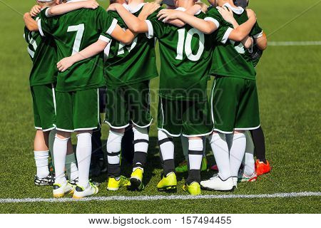 Sports team standing together on field. Football team motivated by coach. Youth soccer match