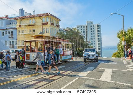 San Francisco, CA, USA - August 16, 2016: Cable Car of San Francisco, Powell-Hyde lines.Tourists crossing the intersection between Hyde and Lombard Street, one of the most crooked streets in the city.