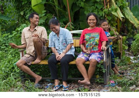 BANGKOK, THAILAND, SEPTEMBER 23, 2016 : A family is sitting on a bench along the railway, smiling and laughing, in the district of Talat Phlu, Bangkok, Thailand